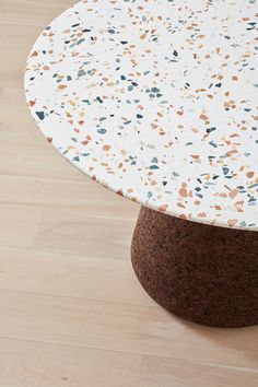 a white table with multicolored speckles sitting on a hard wood floor