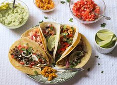 three tacos on a plate with salsa and guacamole