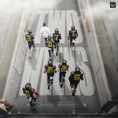 a group of football players walking down the street in uniforms with numbers painted on them