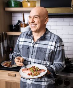 a man holding a plate with food on it in his hands and smiling at the camera