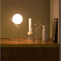 a table with a lamp, vases and other items on it in front of a wall