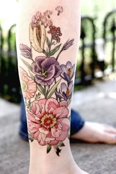 a woman's leg with flowers on it and butterflies flying around the flower tattoo