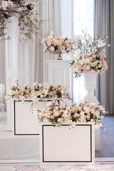 three white vases with flowers in them on display