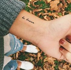 two people holding hands with the word love tattooed on them