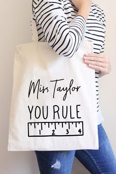 a woman holding a tote bag that says, miss taylor you're 1 / 2