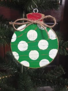 a green ornament hanging from a christmas tree with white polka dots on it