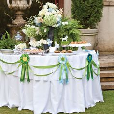 a table topped with lots of food on top of a lush green field covered in flowers