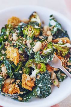 a white bowl filled with broccoli and other food on top of a table