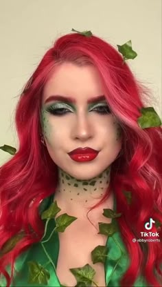 a woman with long red hair and green leaves on her head, wearing makeup in the shape of ivy