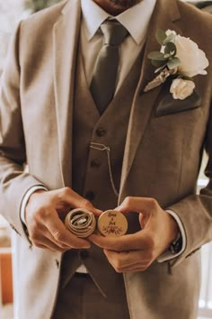 a man wearing a suit and tie holding a small badge in his hand while standing next to a window