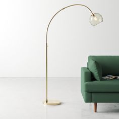 a green couch sitting next to a lamp on top of a white floor in a living room