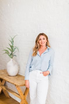 a woman standing in front of a table with a potted plant on top of it