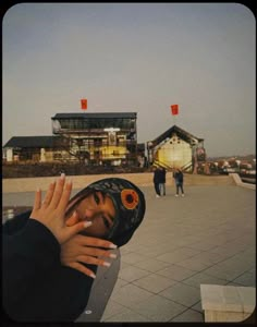 a woman wearing a helmet and holding her hand up to her face while standing in front of a building