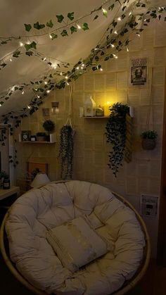 a living room filled with lots of plants and lights hanging from the ceiling above it