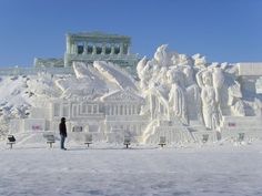 a person standing in front of a building covered in snow with statues on the side