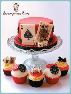 some cupcakes are sitting on a cake plate with playing cards and dice decorations