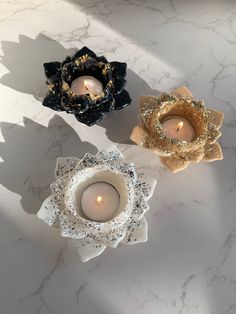 three candles sitting on top of a white table next to each other in different shapes and sizes