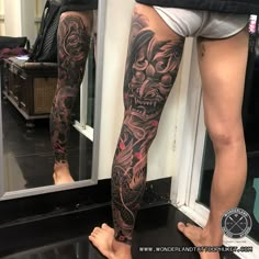 a man's leg with tattoos on it and his reflection in the mirror behind him