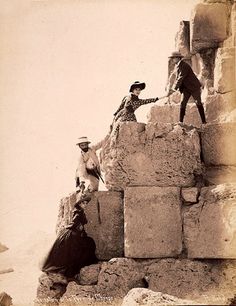 an old photo of two men on top of a rock formation with one holding the hand of another man