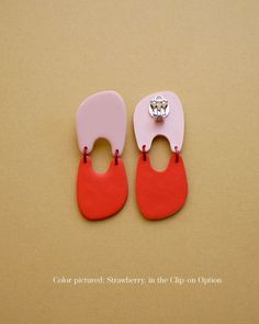 two pairs of pink and red shoe clips on a tan surface with a diamond in the middle