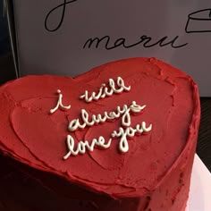 a red heart shaped cake with writing on it