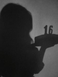 the shadow of a person holding a skateboard in front of a number thirteen sign