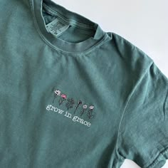 My absolute favorite tee!  'grow in grace' is stitched below a variety of wildflowers  in shades of blush, coral, sage and mustard.  Please wash on gentle cycle and dry on low.  If you are wanting a different design, wording, or a different clothing style, please send me a message so we can discuss the details. Please include thread color at checkout If you need this order rushed, please add these to your cart: https://www.etsy.com/listing/1043569716/rush-my-order-for-t-shirts?ref=shop_home_active_19&frs=1 Rush my order + Priority shipping, click here: https://www.etsy.com/listing/1043567696/rush-my-order-priority-shipping-for-t?ref=shop_home_active_35&frs=1 Green Cotton Top With Embroidered Graphics, Christian T Shirts Designs, Cute Embroidered T-shirt For Spring, Affordable Cute T-shirt With Floral Embroidery, Cute Floral Embroidery Crew Neck T-shirt, Casual Everyday Embroidered T-shirt, Green T-shirt With Floral Embroidery, Green Cotton T-shirt With Floral Embroidery, Christian Clothing Brand