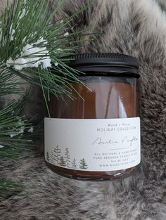 a jar of holiday candles sitting on top of a fur covered floor next to a pine tree