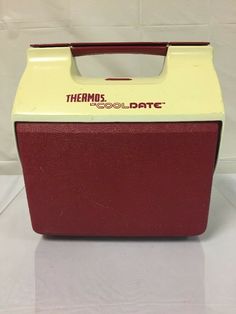 a red and white cooler with thermos logo on it's lid sitting on a table