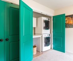 a washer and dryer sitting in a room with green doors leading to another room