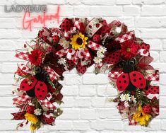 a ladybug wreath with sunflowers and daisies on a brick wall