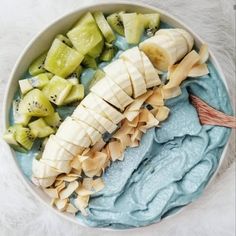 a white bowl filled with sliced bananas and kiwis on top of blue food