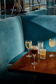 three different types of wine glasses on a wooden table in front of a blue couch