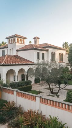 a large white house with red tile roof and orange tiles on the walls, surrounded by greenery