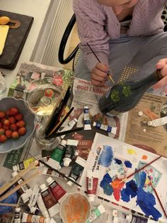 a woman sitting at a table with lots of art supplies