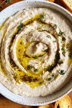 a white bowl filled with hummus and olive oil on top of toasted bread