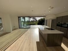 an empty kitchen with wooden floors and glass doors leading to the outside patio area that overlooks a large open field