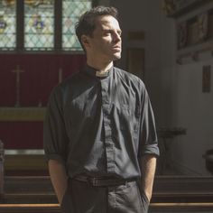 a man standing in front of a church pew with his hands on his hips and looking off to the side