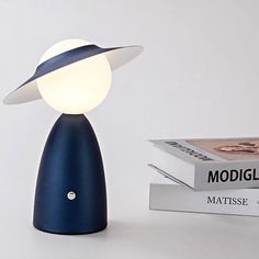 a blue lamp sitting on top of a white table next to books and a book