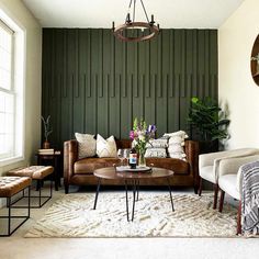 a living room filled with furniture and a large green screen behind the couch is a round coffee table