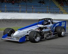 a blue and white race car driving around a track