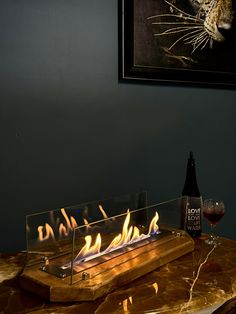 a table with a bottle of wine and a glass on it that has flames in it