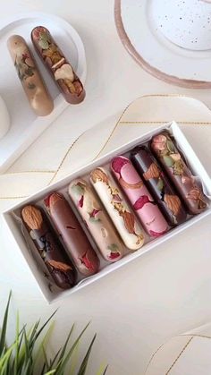 a box filled with assorted donuts on top of a white table next to plates