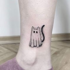 a small black and white cat tattoo on the ankle