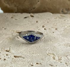 a diamond and blue sapphire ring sitting on top of a rock