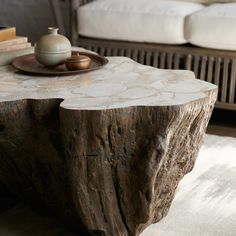 a coffee table made out of a tree stump with a vase on top and books in the background