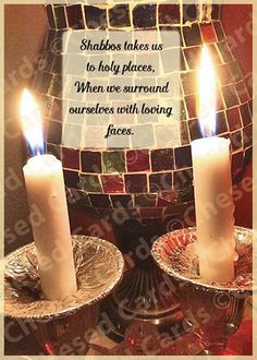 two lit candles sitting in front of a mosaic tile wall with a quote on it