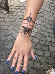 a woman's hand with a black spider tattoo on her left wrist and blue nail polish