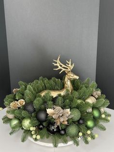 a white plate topped with green and black ornaments next to a gold deer figurine