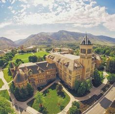 an aerial view of a large building in the middle of a green field and mountains